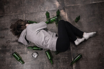 looks depressed with empty beer bottles. High angle view of drunk man  with bottles and ashtray