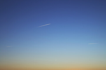 Obraz premium La estela de tres aviones al atardecer. Aviones volando en el cielo apenas visible en la distancia pero donde se observa la estela dejada en su trayectoria.