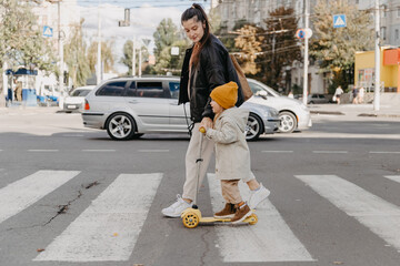 mother brings a child riding a scooter on the crosswalk © Ananass