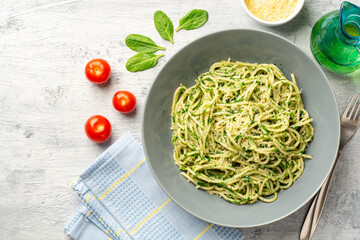 Spaghetti pasta with spinach sauce and parmesan cheese on concrete background