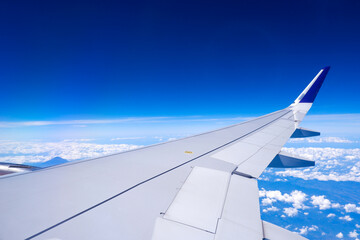 Obraz premium Photo of airplane wing with clouds background, horizon line and clear blue sky