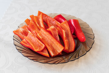 Sliced red pepper on a brown plate. The plate is on a white tablecloth.