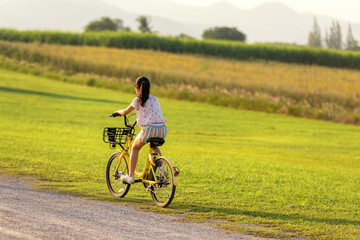 Fototapeta premium Family Happy. Asia gird happy and relax outdoor with bicycling at the garden meadow in sunset. Lifestyle Family Concept