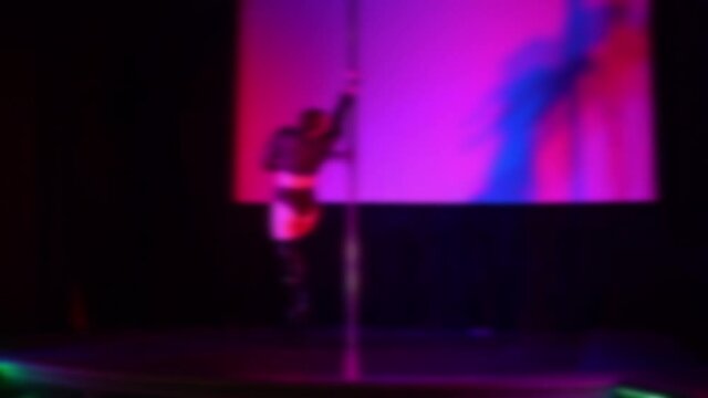 Defocused view, sexy woman dancing on a stage in a strip club