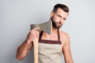 Portrait of attractive brutal guy wearing apron holding wooden ax cutting shaving beard isolated...