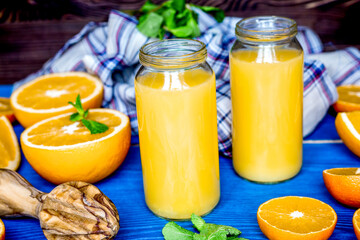 healthy orange cocktail with mint leaves in bottle on kitchen background