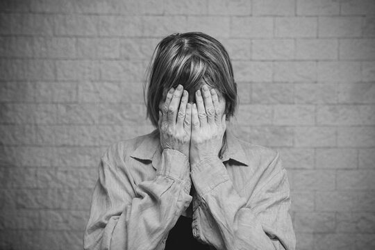 Senior Woman Addict And Alcoholism Alone Depression Stress Sitting On The Floor With Her Head In Her Hands. The Concept Psychological Health, Panic Attack. Social Documentary Concepts Black And White