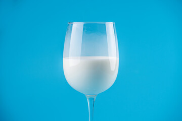 White fresh milk in a glass on blue background