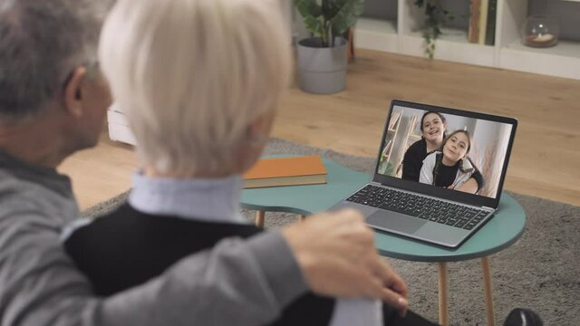 family members video conference call grandparents talking to children using computer,old man and woman sitting on couch make a videocall and chat with grandchildren kids