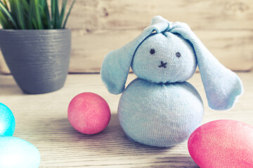 Toy Easter bunny and painted eggs on a wooden background.