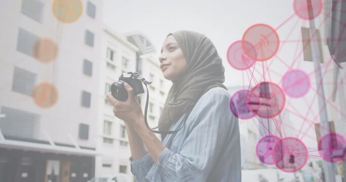 Animation of a network of pink and red icons with woman wearing hijab taking photos in street