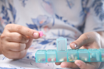 women hands taking medicine from a pill box 