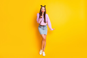 Fototapeta na wymiar Full size photo of optimistic pretty brunette girl blow kiss closed eyes wear pink sweater skirt sneakers isolated on yellow background
