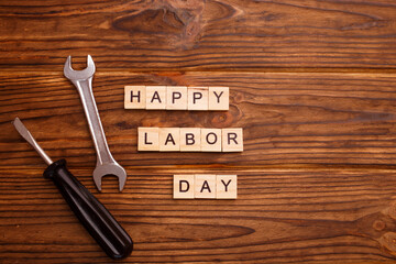 Happy Labor Day greeting card concept. HAPPY LABOR DAY wooden text with tools on wooden background. Flat lay, top view.