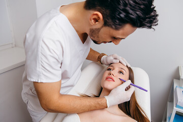 Fototapeta premium Young brunette woman receiving plastic surgery injection on her face, closeup portrait