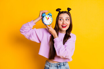 Fototapeta premium Photo of young smiling happy positive girl look at clock waiting time schedule isolated on yellow color background