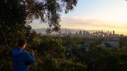 Man wearing a mask takes photos of a beautiful city skyline and sunset. A reminder to focus on the positives during the coronavirus-COVID-19 outbreak.
