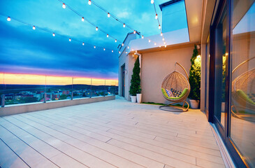 rooftop deck patio area with hanging chair and lights on a sunset