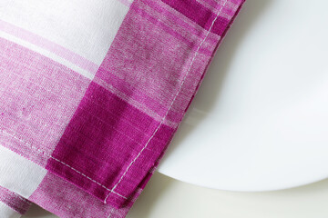 empty white dining plate and pink plaid kitchen towel close up