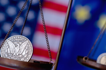 US Dollar coin and EU currencies on weighing scale against Unated States and European Union flags as symbol of  trade war, economic conflict and  relations. Close up.