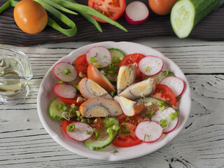 Slices of smoked egg, tomatoes, cucumber, radish with green onions and spices in a plate, fork, olive oil on a white wooden table, flat layout. Recipe for vitamin salad with chicken eggs