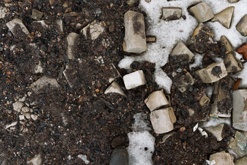 fragments of bricks, coal scattered in the snow at the construction site