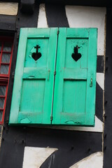 green old medieval shutter with heart and cross of a red wooden window from a half timbered house