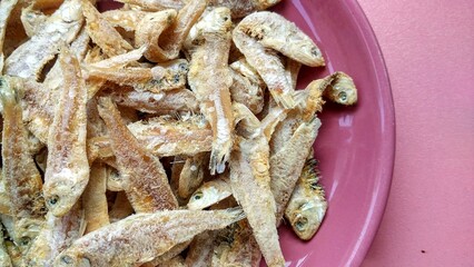A pile of small salted fish, dried sea fish is preserved using sea salt. Traditional Indonesian seafood on plate