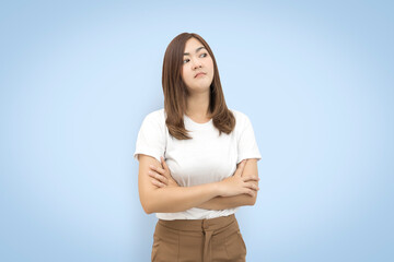 Portrait of an upset unsatisfied asian woman standing with arms folded and looking away isolated on blue background. with clipping paths.