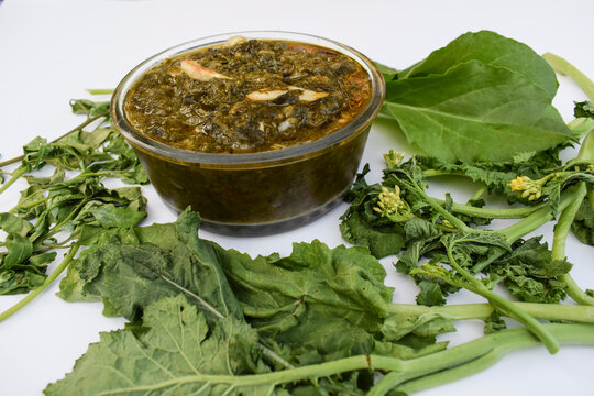 Indian homemade curry Sarson ka saag ki sabji served in transparent bowl garnished with fried green chilly, red chilly and garlic cloves. Authentic North indian Punjabi sabzi. Decorated with raw leaf