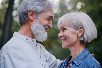 Outdoors portrait of happy elderly couple embracing in summer park.