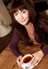 Lifestyle and people concept: Beautiful young woman drinking a tea in kitchen