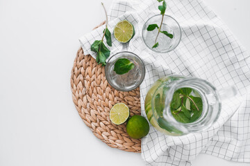 Detox water with lime fruit and mint leaves in jar and glasses. Flat lay, top view