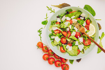 Healthy fresh salad of vegetable, tomatoes, spinach, arugula in a green plate on a white background. Top view. salat with tomatoes cherry and green leafs. Mediterranean salad with cherry tomatoes	