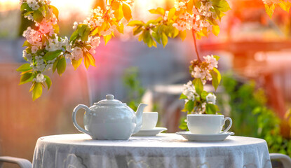 Elegant tea set on a lace tablecloth in sunlight. Outdoor brunch spring mood.