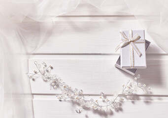 Jewelry made of beads, gift box, veil on a white wooden background.