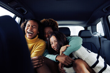 Group of diverse young female friends laughing in a car - obrazy, fototapety, plakaty