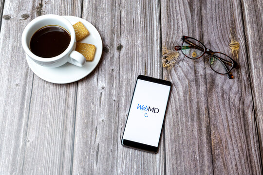 03-03-2021 Portsmouth, Hampshire, UK A mobile phone or cell phone laid on a wooden table with the WebMD app open next to a coffee