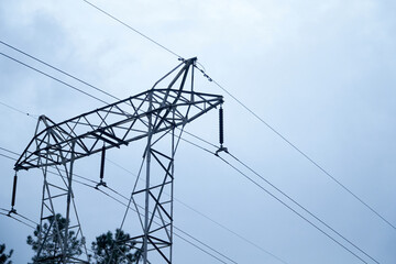 high voltage electrical tower with blue sky in the background and green bushes in the distance....