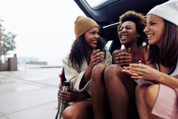 Laughing friends warming up after a winter swim with tea