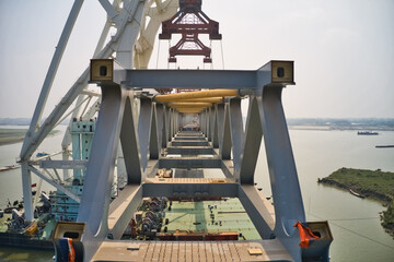 Aerial view of a building site while assembling the Padma bridge, the longest rail and highway bridge in Bangladesh crossing the Padma river, Zajira, Dhaka, Bangladesh.