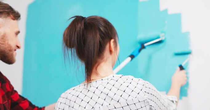 Close up of beautiful young Caucasian woman painting wall in new apartment using paint roller tired from work reparing home House redecoration and home construction while renovating and improving