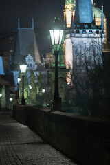 Fototapeta premium street lantern of Charles Bridge at night in lockdown and stone tower in the background
