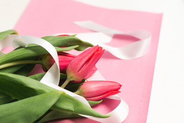 Bouquet of pink tulips with white ribbon on pink background, soft focus