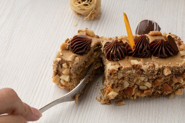 with a fork a person cutting some cake filled with walnut with chocolate decoration, delicious dessert in a studio