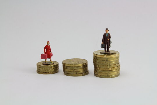 zwei kleine Figuren Frau und Mann stehen auf unterschiedlich hohen Stapeln aus Münzen steht für ungleiche Bezahlung und Gleichberechtigung 