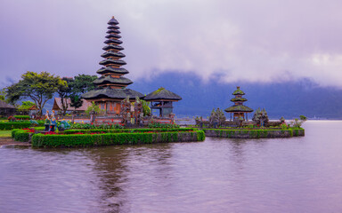 Obraz premium Pura Ulun Danu Bratan temple in Bali island. Beautiful balinese temple during sunrise. Balinese landmark. Cloudy sky. Water reflection. Bratan lake, Bali