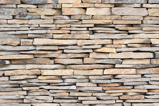 Stone wall of natural stones. Brickwall texture background. Stone Veneers, cladding wall made of stacked slabs of natural rocks