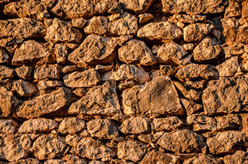 Dry stone wall, close up. Stone wall near the house in countryside at sunset. A traditional dry stone wall in the field. Medieval stone wall pattern. Background.
