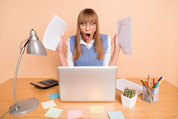 Photo portrait of woman in blue vest shocked overwhelmed staring with documents deadlines isolated on pastel beige color background